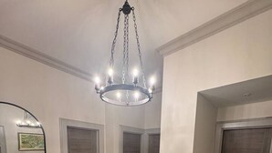 Un'ampia sala con pavimento in legno, un grande specchio e un lampadario.