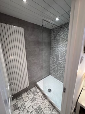 Ein modernes Badezimmer mit Dusche, gemusterten Fliesen und einer weißen Tür.