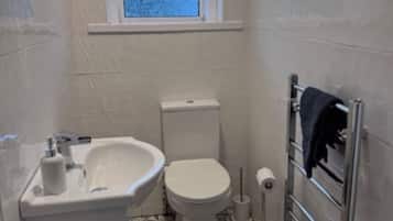 Ein kleines Badezimmer mit Toilette, Waschbecken und Fenster.