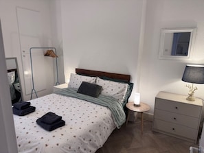Ein Schlafzimmer mit einem Bett, Nachttisch und einem kleinen Fenster.