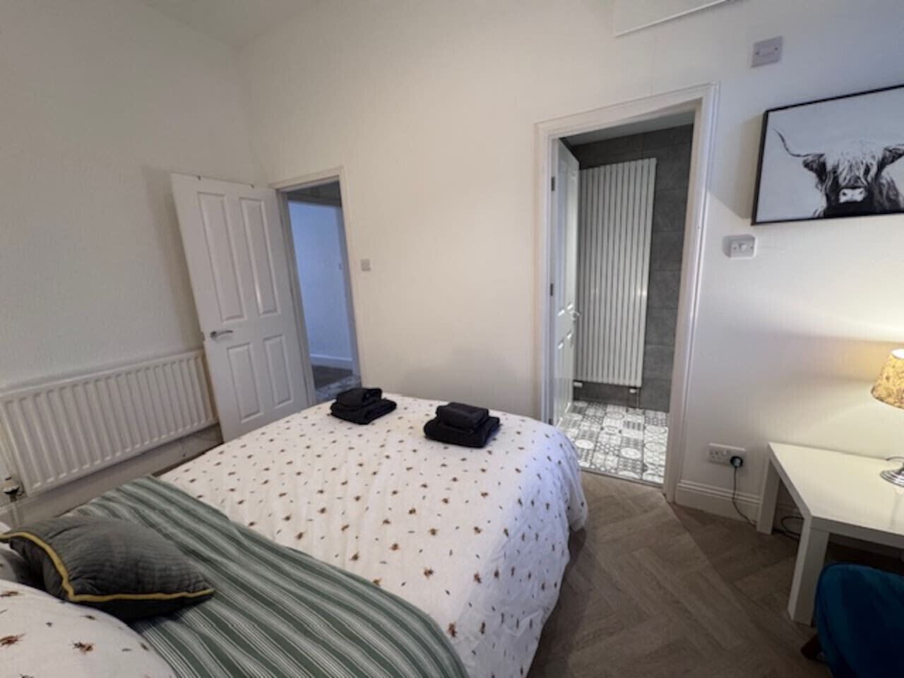 A hotel room with a bed, a desk, and a door leading to a bathroom.