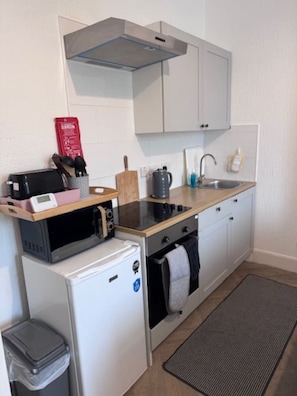 Eine kleine Küche mit Mikrowelle, Toaster, Wasserkocher, Spüle und kleinem Kühlschrank.