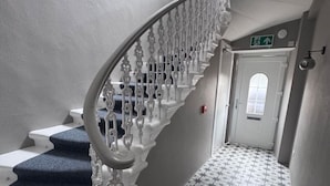 Eine Treppe mit weißer Handläufer und blau beflochtenen Stufen, die zu einer Tür mit einem sternförmigen Boden führt.