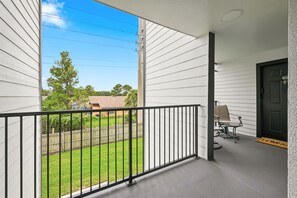 Un balcon avec une balustrade en métal, une porte et une petite table avec des chaises.
