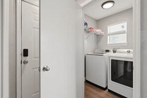 Une buanderie équipée d’un lave-linge, d’un sèche-linge et d’une étagère où sont pliés les vêtements.