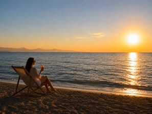 A person sitting on a beach chair facing the ocean at sunset. - Lake Sevan Private Cottage with Yard (Shoghakat)