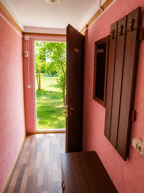 A room with a wooden door leading to a grassy outdoor area, a wooden dresser, and a wall-mounted coat rack. - Lake Sevan Private Cottage with Yard (Shoghakat)