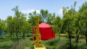 An outdoor area with a red canopy structure, surrounded by greenery and trees. - Lake Sevan Private Cottage with Yard (Shoghakat)