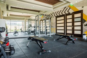 Ein Fitnessstudio mit verschiedenen Trainingsgeräten, darunter Bänke und Kraftgeräte.