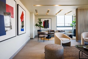 Een modern interieur met een zithoek, kunstwerken aan de muren, en een groot raam dat voor natuurlijk licht zorgt.