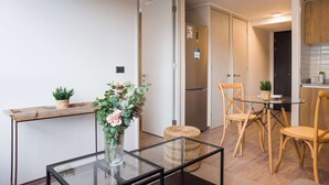 Een moderne keuken met houten kastjes, een roestvrijstalen koelkast en een eethoek met een glazen tafel en houten stoelen.
