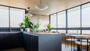 A modern kitchen with a central island, large windows, and indoor plants. - Beautiful 2BR Apt in Las Condes with Pool & Views (Las Condes)