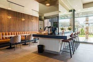 A modern cafe with a wooden wall, leather seating, a bar area, and a view of the outdoors.