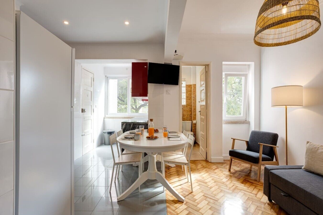 A modern dining area with a round table, chairs, and a bottle of orange juice.
