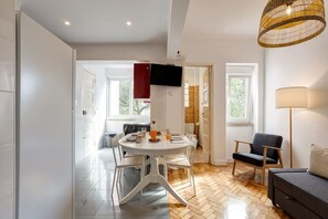 A modern dining area with a round table, chairs, and a bottle of orange juice. - Bright, Custom-Built Apartment with Air Conditioning in Areeiro (Lisbon)