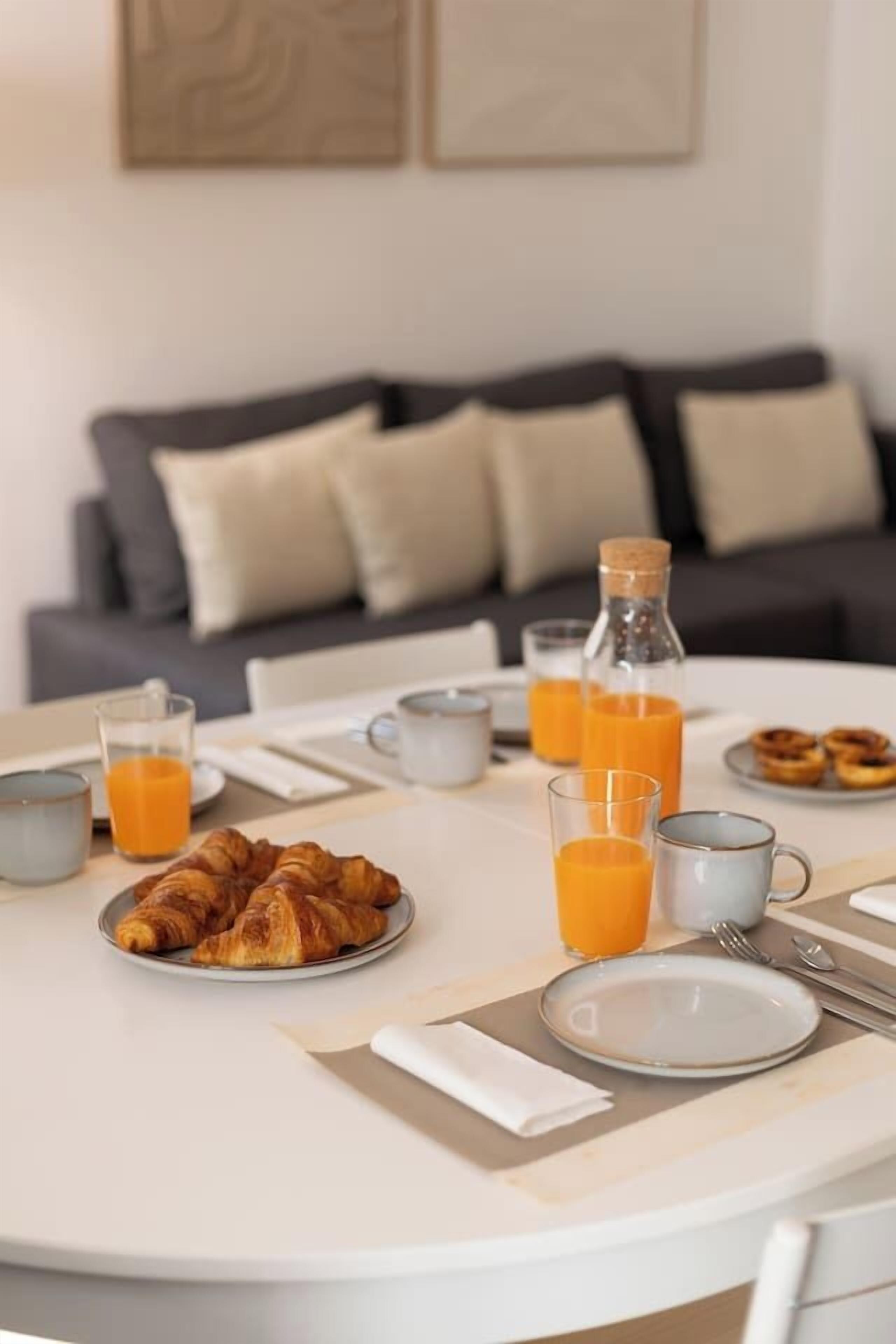 Ein Frühstückstisch mit Croissants, Orangensaft und einer Flasche.