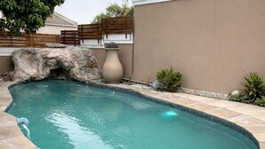 A swimming pool with a rock feature and a large vase. - The Seamless Oasis (Cape Town)