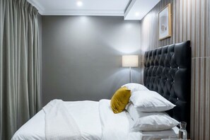 Een hotelkamer met een bed, een lamp en een ingelijst schilderij aan de muur.