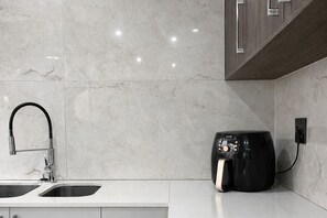 Een moderne keuken met een dubbele spoelbak, een inbouw afzuigkap en een aanrecht met een koffieapparaat.