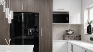 A modern kitchen with a refrigerator, microwave, and cabinets. - The Seamless Oasis (Cape Town)