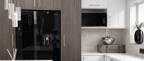 A modern kitchen with a refrigerator, microwave, and cabinets.