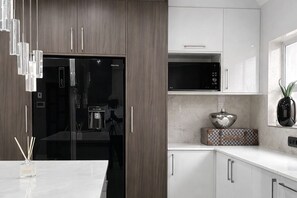 Een moderne keuken met een koelkast, magnetron en kasten.