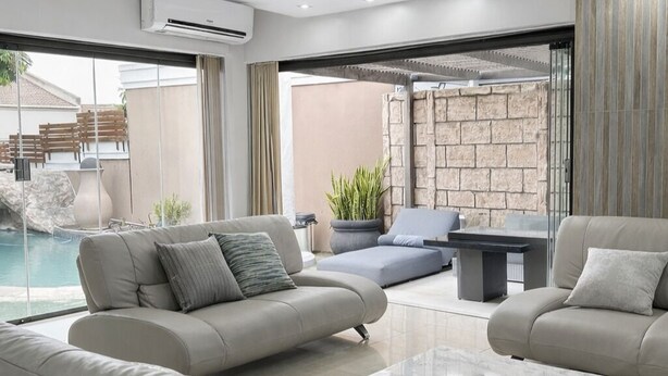 A modern living room with a pool view, a stone wall, and a glass door leading outside. - The Seamless Oasis (Cape Town)