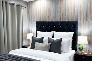 Ein Hotelzimmer mit einem großen Bett, zwei Nachttischen mit Lampen und einer gestreiften Wand.