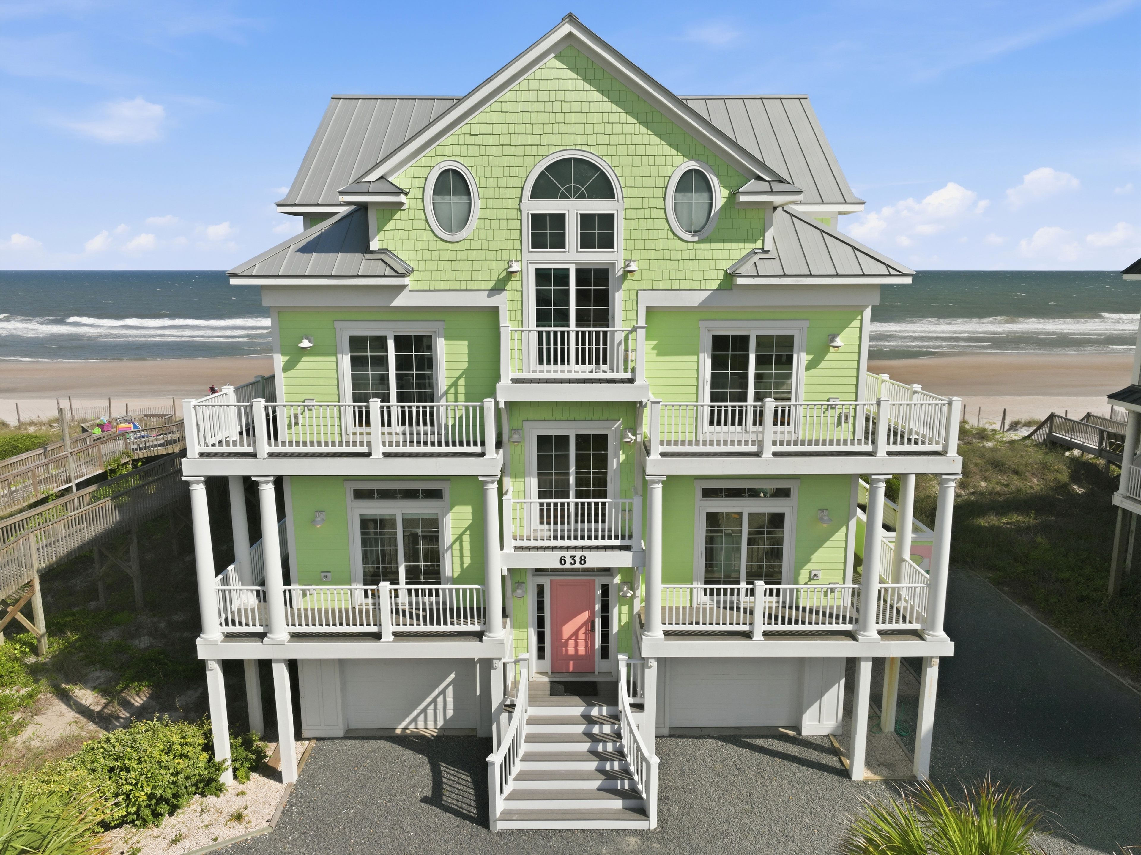 A two-story building with a balcony, a garage, and a view of the beach.