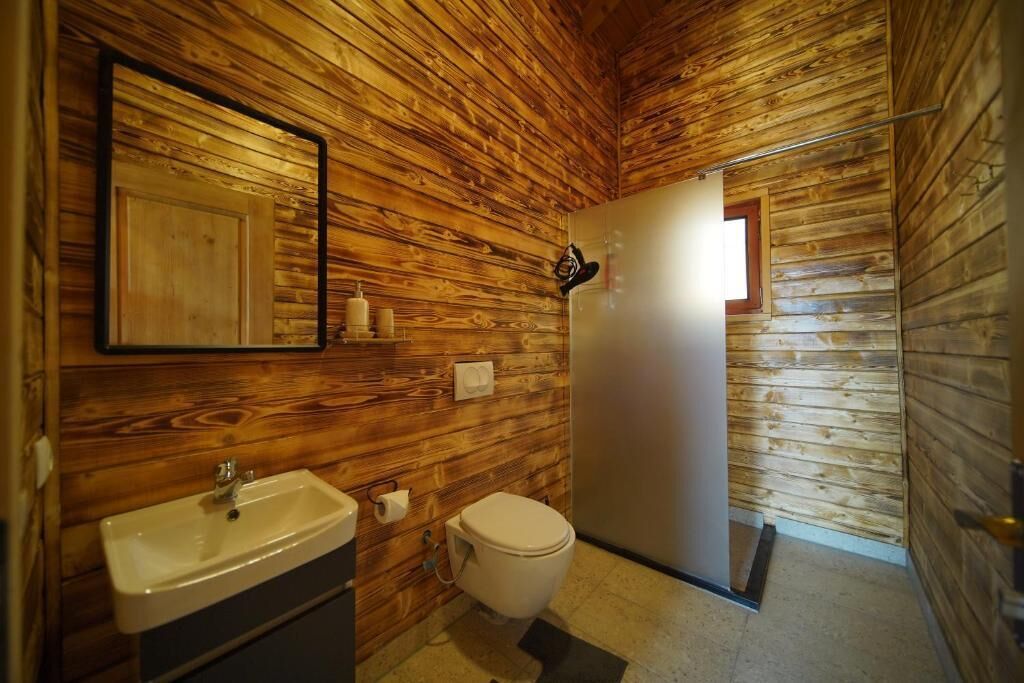 A wooden-paneled bathroom with a sink, toilet, and a mirror.
