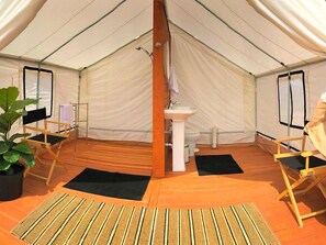 A tent with a central pillar, a sink, and foldable chairs.