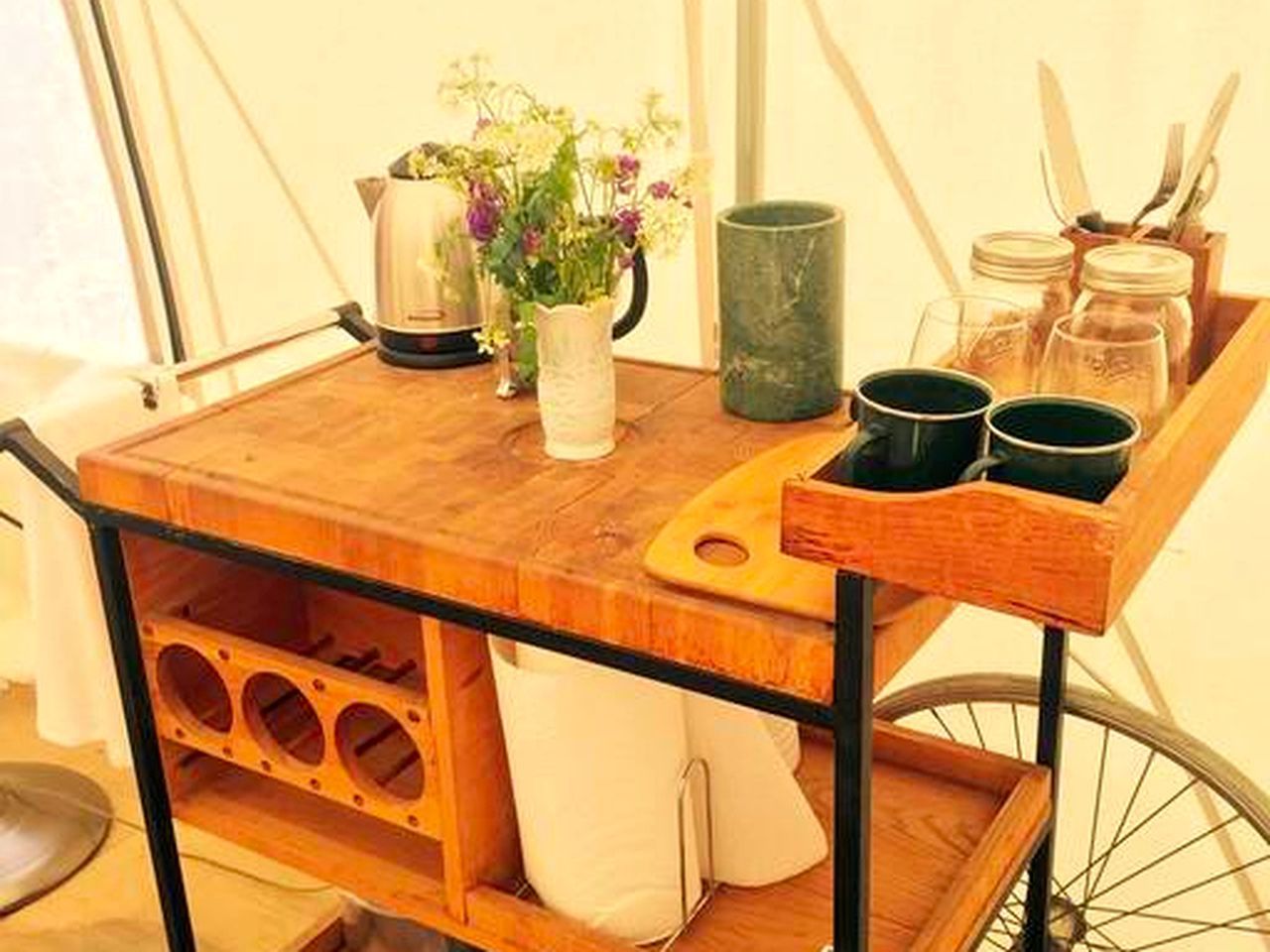 Ein Holzwagen mit Schneidebrett, Blumen in einer Vase und Küchenutensilien.