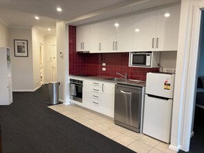 A modern kitchen with white cabinets, a stainless steel dishwasher, and a microwave. - Sun-Drenched 1BD Apt in the heart of South Yarra (South Yarra)