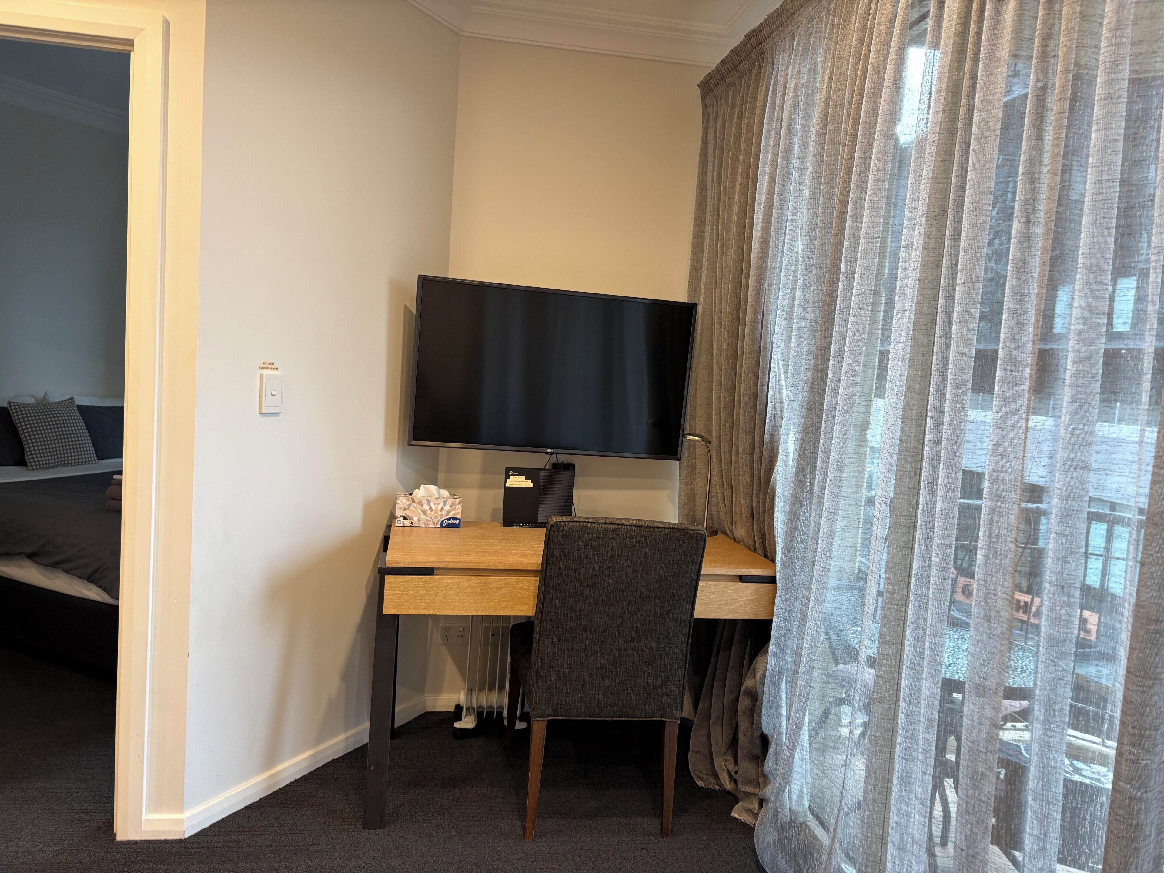 Une chambre d’hôtel équipée d’un bureau, d’une télévision et d’un lit.
