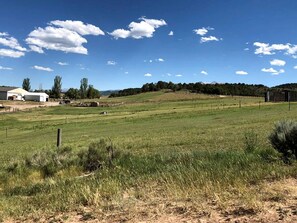 Paisaje rural con un campo cercado, un edificio y cielo despejado.