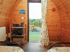 Ein gemütliches Blockhaus-Interieur mit Holzausstattung, einem Warnschild, einem Fenster mit Blick ins Freie und einem kleinen Tisch mit Stühlen draußen.
