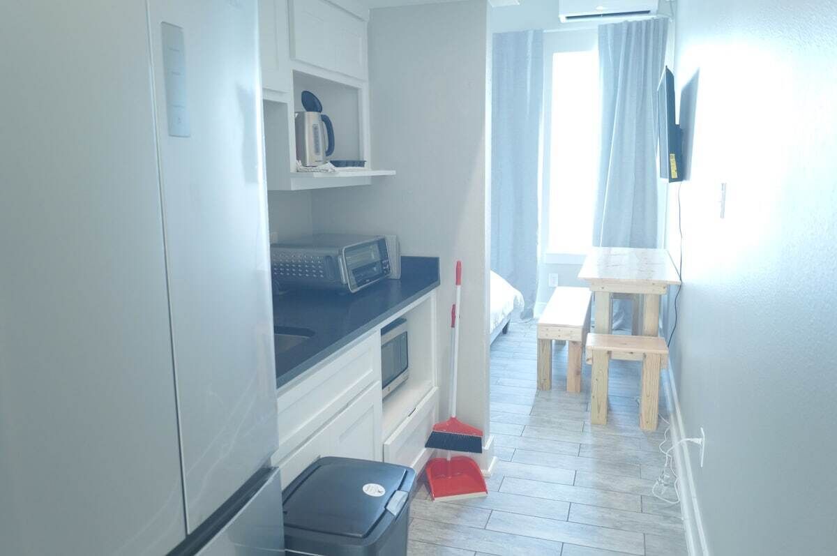 Una cocina compacta con microondas, cafetera y una pequeña mesa con sillas.