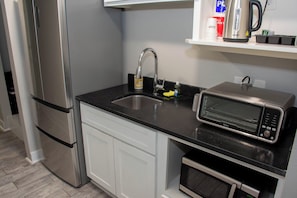 A kitchen with a stainless steel refrigerator, a sink with a faucet, a microwave, and a small oven. - Casa Dora Beachfront Coast (Gilchrist)