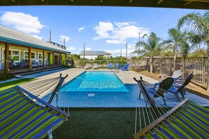 A backyard with a swimming pool, lounge chairs, and a covered patio area. - Welcome to SGI Refuge! (St. George Island)