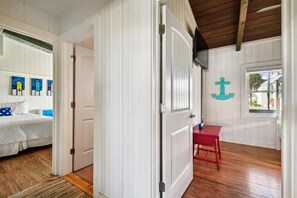 Ein Zimmer mit einem Bett, einem roten Sessel und einem Fenster mit Anker-Verzierung.