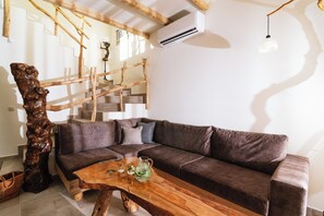 Een moderne woonkamer met een bruine leren bank, een houten salontafel en een trap met houten leuningen.