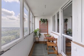 A narrow balcony with a table and chairs, a potted plant, and a view of the cityscape. - Lumina 3room Apart with Balkony & Center (Warszawa)