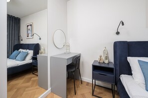Quarto moderno e bem iluminado, com uma cama, escrivaninha e cadeira, e um padrão de piso em padrão herringbone.
