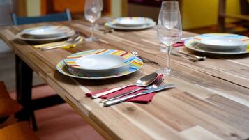 Une table de salle à manger en bois, mise avec des assiettes, des couverts et un verre.