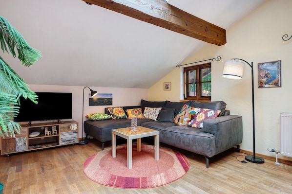 A cozy living room with a sofa, a flat-screen TV, a coffee table, and a lamp.