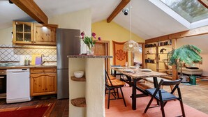 Una cocina con armarios de madera, un refrigerador de acero inoxidable y un comedor con mesa y sillas.