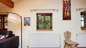 Una habitación con ventana de madera, un radiador, una lámpara de pie y un cuadro en la pared.