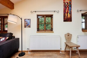 A room with a wooden-framed window, a radiator, a standing lamp, and a painting on the wall.