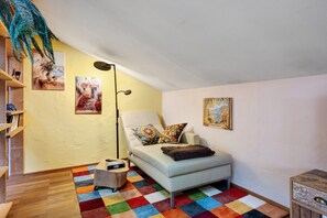 Una habitación acogedora con un sofá blanco, alfombra colorida y obras de arte en las paredes.