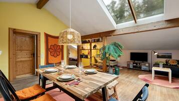 A dining area with a wooden table, orange cushions, and a hanging light fixture.